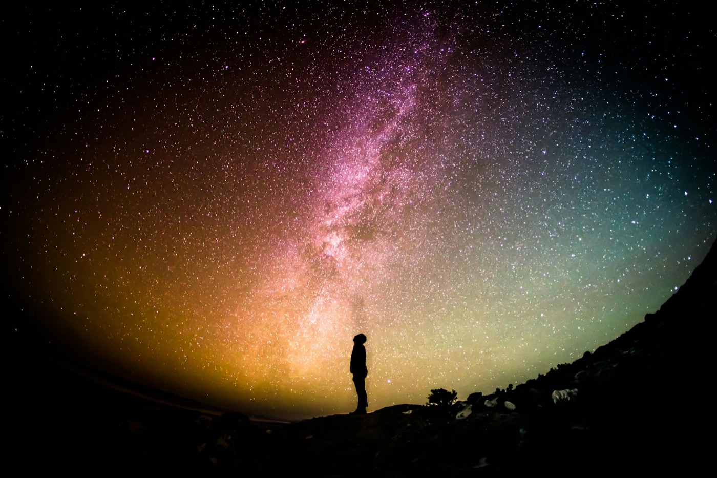 A lone figure beneath a glowing violet galaxy