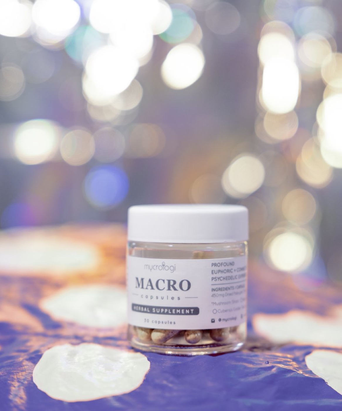 A jar of Mycrologi Macro capsules on violet fabric with soft light behind