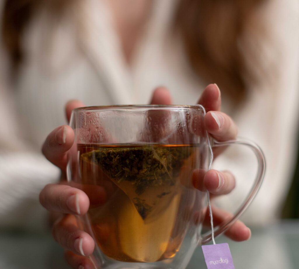 Two hands around a glass cup of Longevity Tea